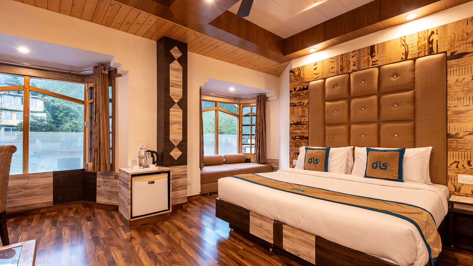 A hotel room in Bhagsunag featuring a large bed, wooden floors, a wooden ceiling, and windows with a view - DLS Meghavan Resort